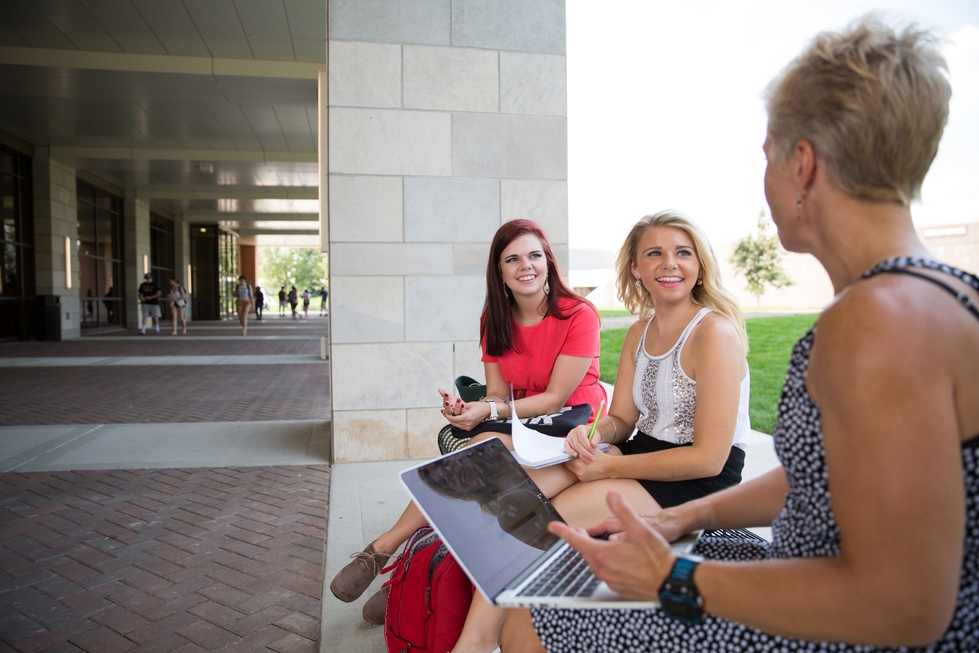 Professor with two students sitting outside.